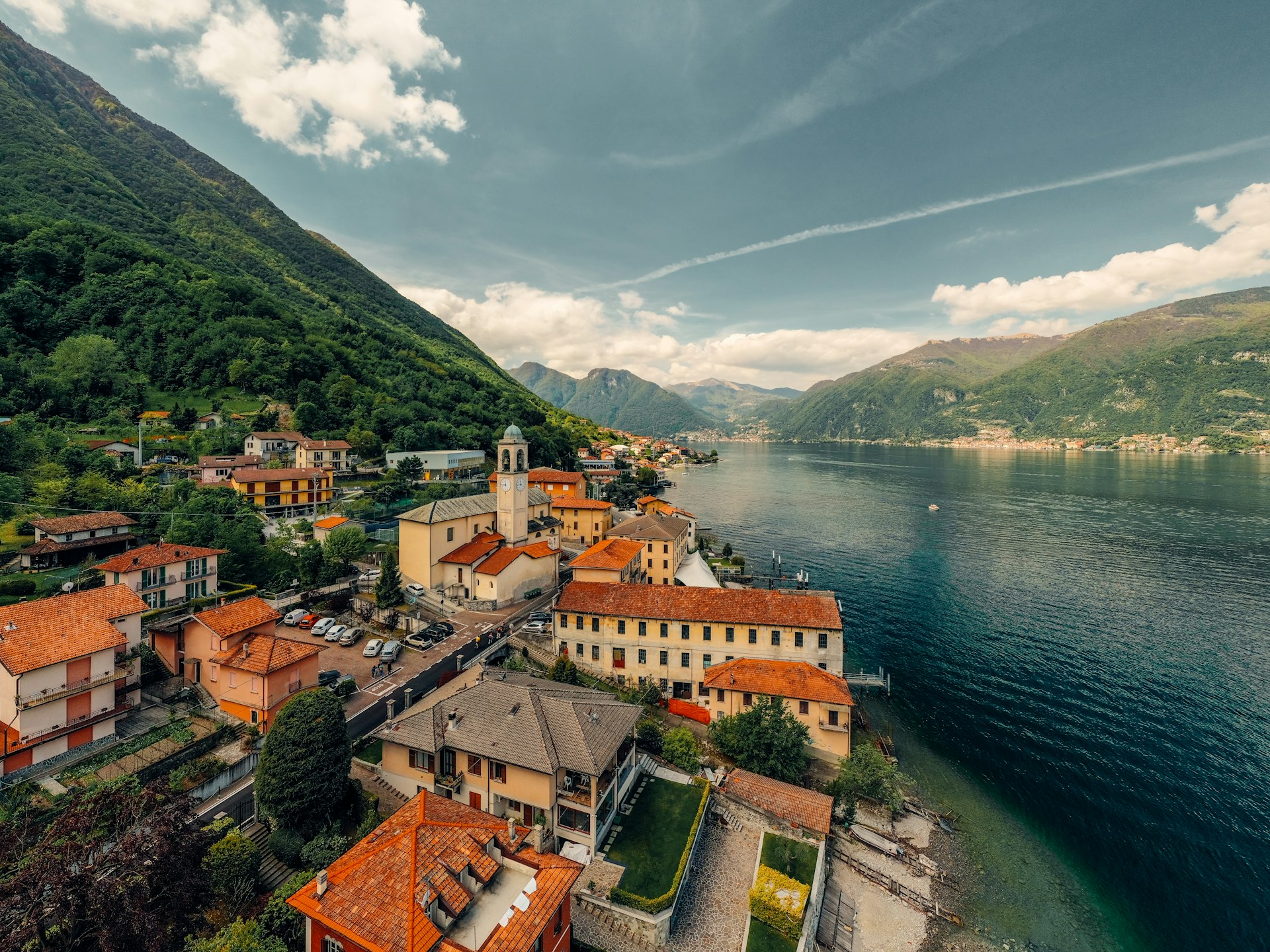 brown and white concrete building near body of water under white clouds and blue sky during
